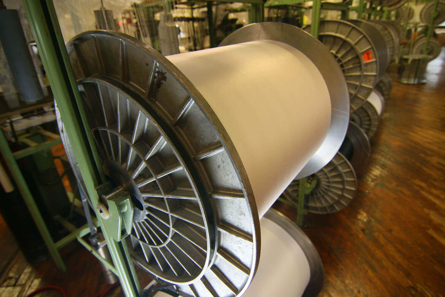 Close up of a large roll of white fabric being stored inside a textile mill