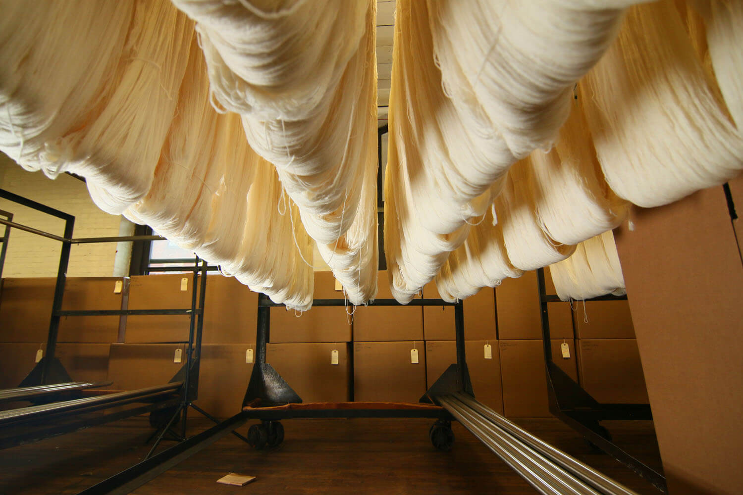 Sections of white fabric hanging on a storage rack inside a textile mill