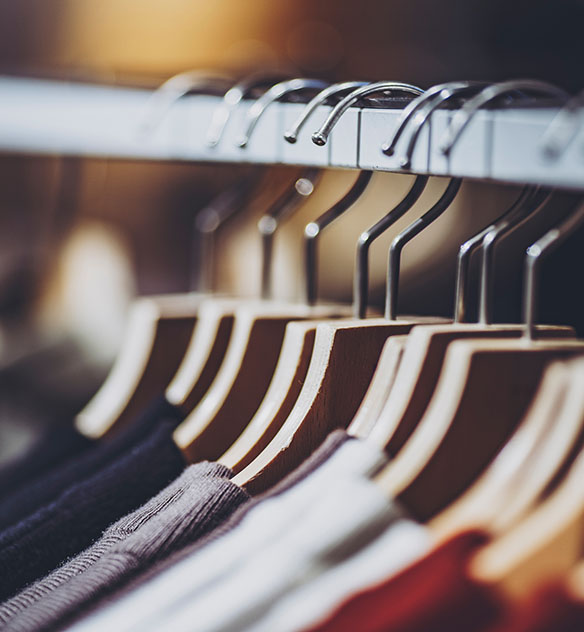 Close-up of apparel with hangers hung on a clothing rack.