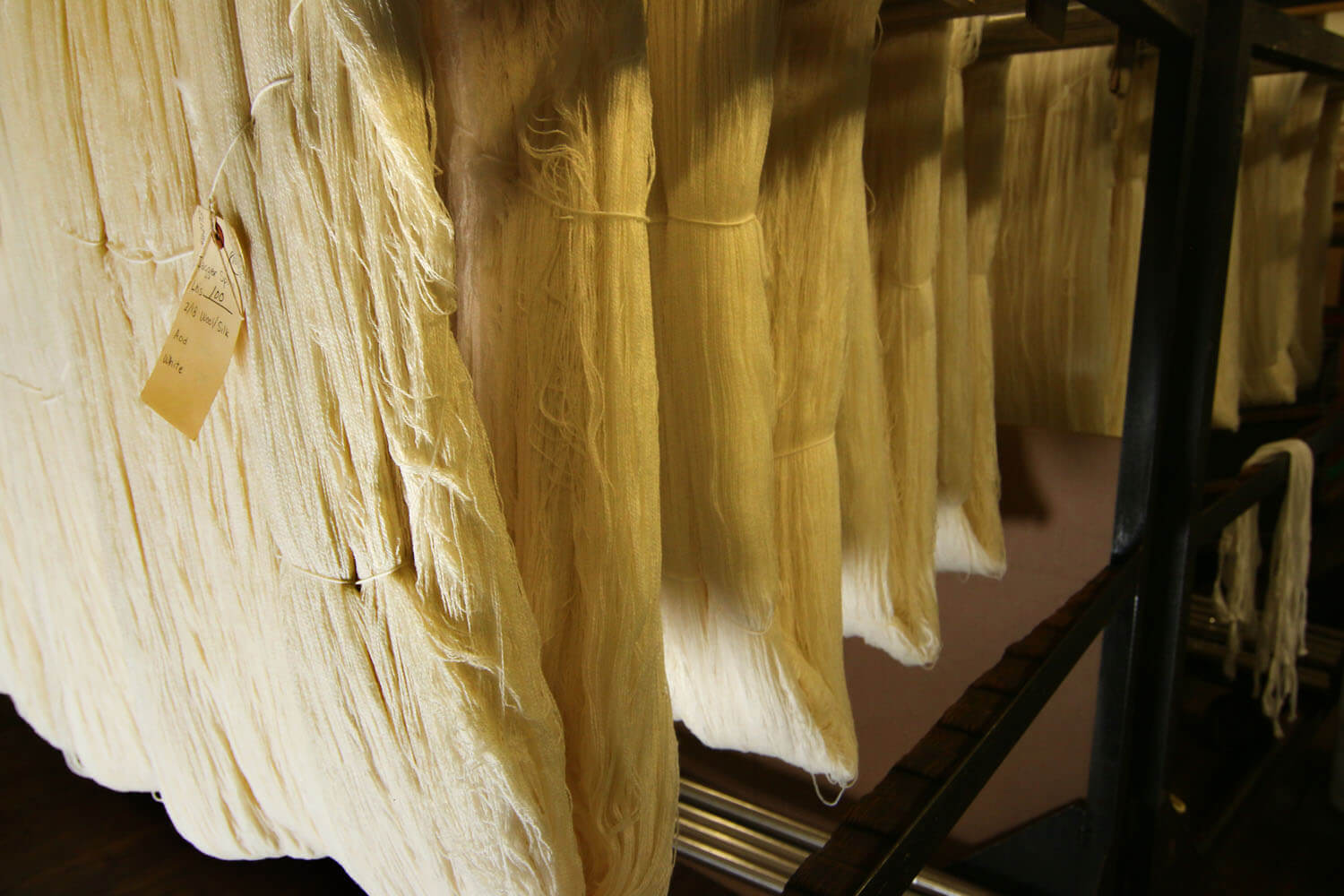 Thick sections of tan fabric being hung together in a textile mill