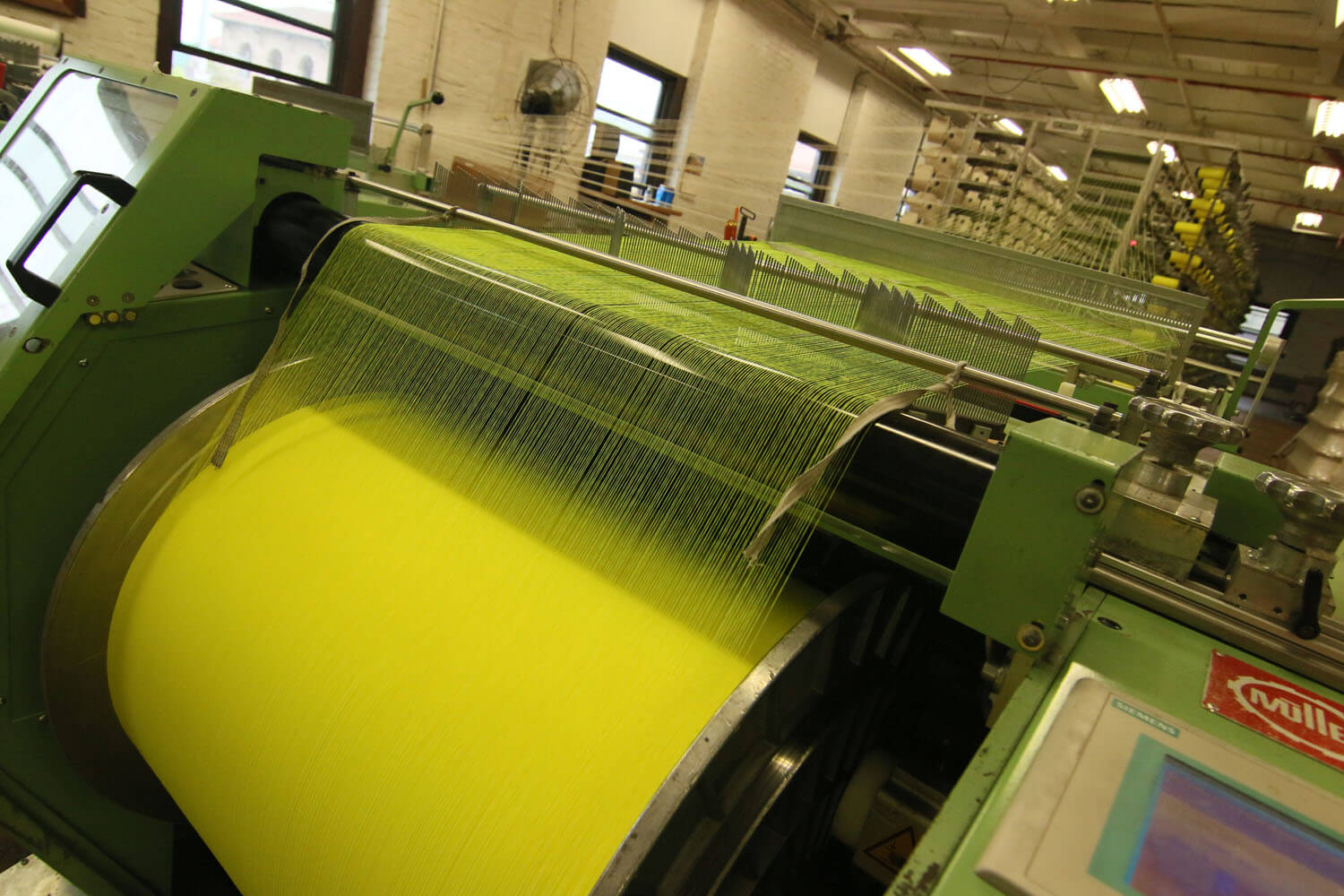 Yellow fabric being rolled into a large spool during the textile manufacturing process