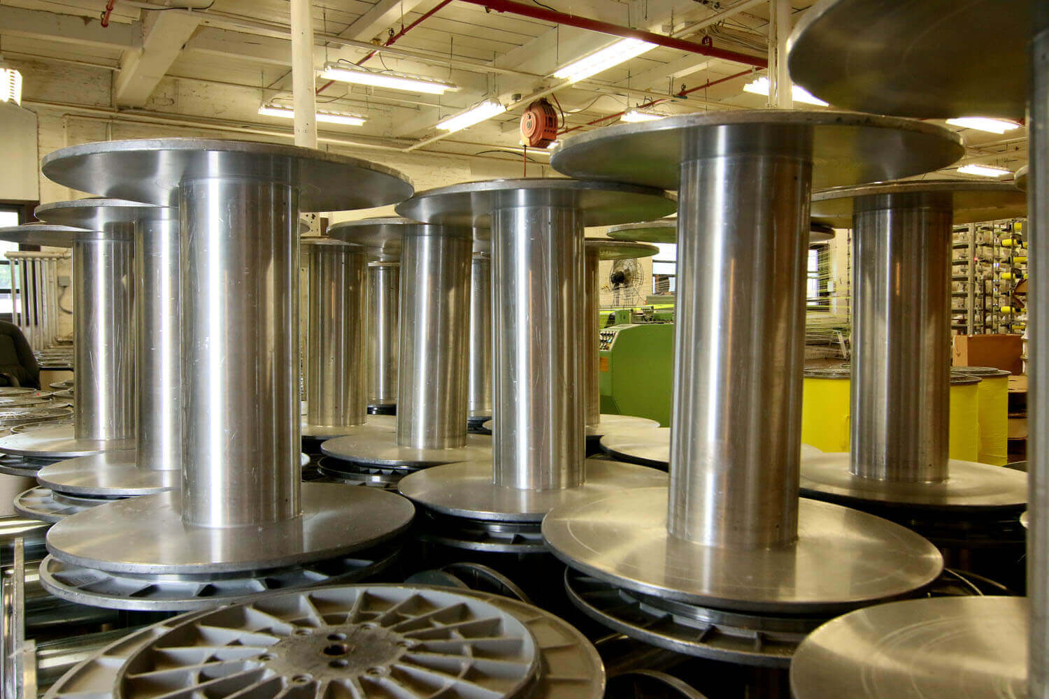 Several large silver empty fabric roll holders inside of a textile facility