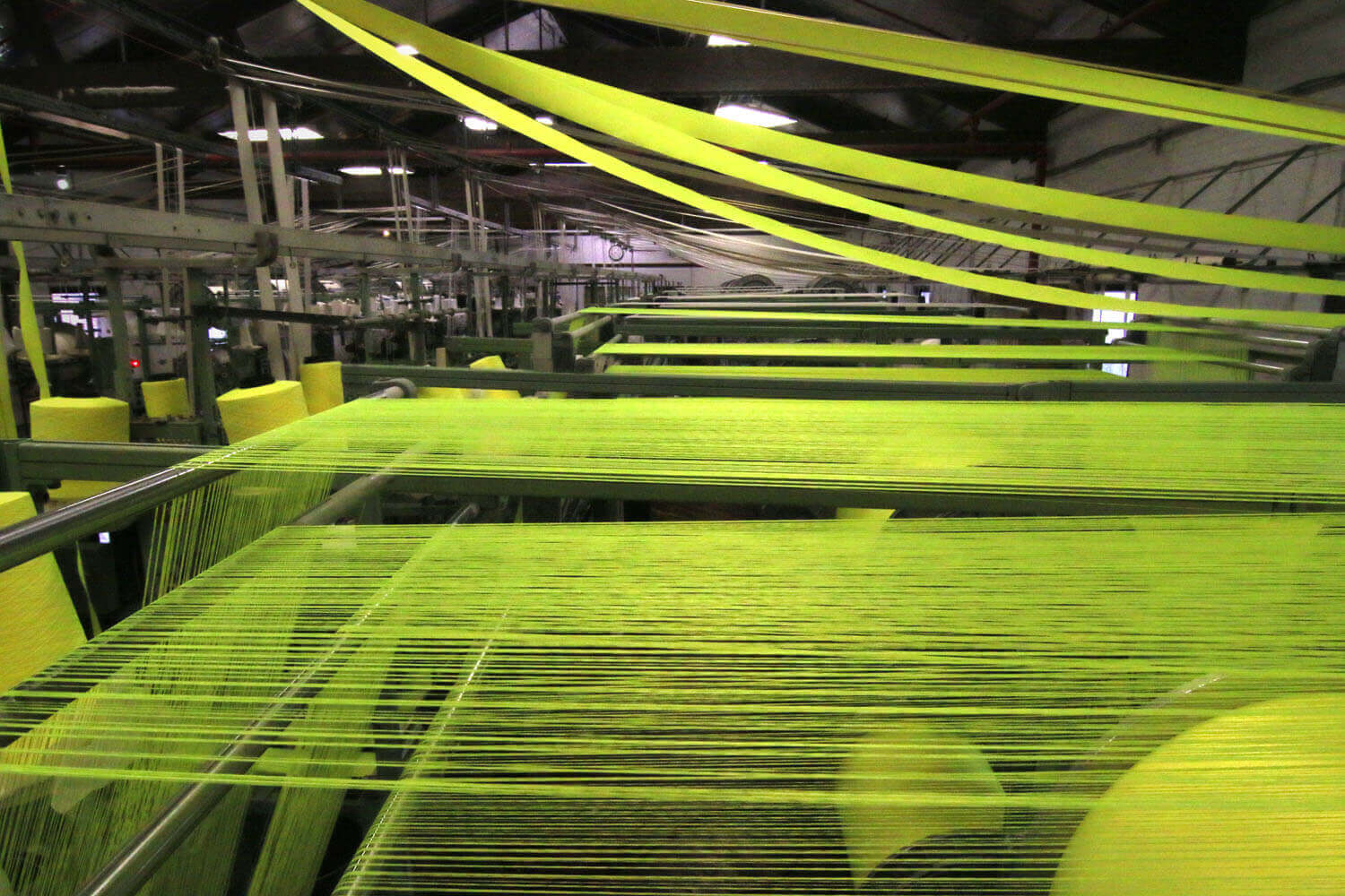 Textile machinery processing strands of yellow fabric