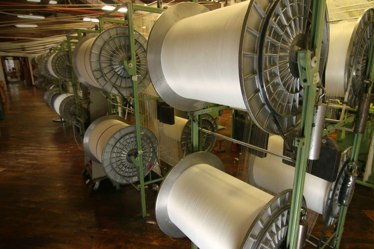 Large spools of white fabric stored inside a textile facility