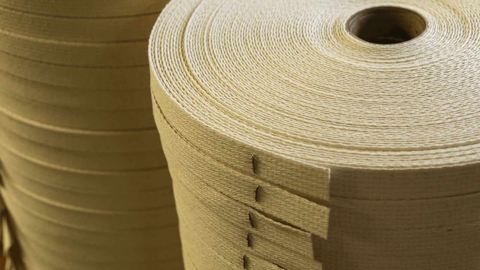 Dozens of spools of tan thread stacked on top of each other inside the Wayne Mills facility