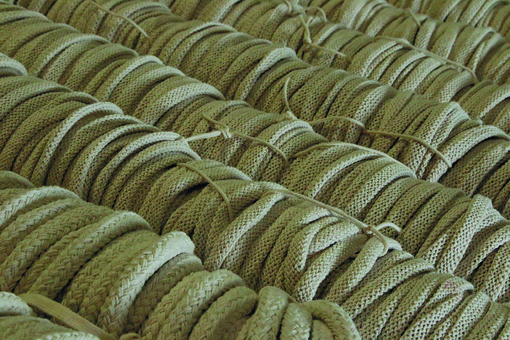 Dozens of dark green drawstrings being processed in a textile facility
