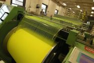 Yellow fabric being rolled into a large spool during the textile manufacturing process