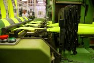 A machine in a textile mill manufacturing large pieces of yellow fabric with an employee in the background