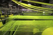 Textile machinery processing strands of yellow fabric