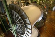 Close up of a large roll of white fabric being stored inside a textile mill