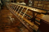 A large wooden piece of textile machinery manufacturing white fabric
